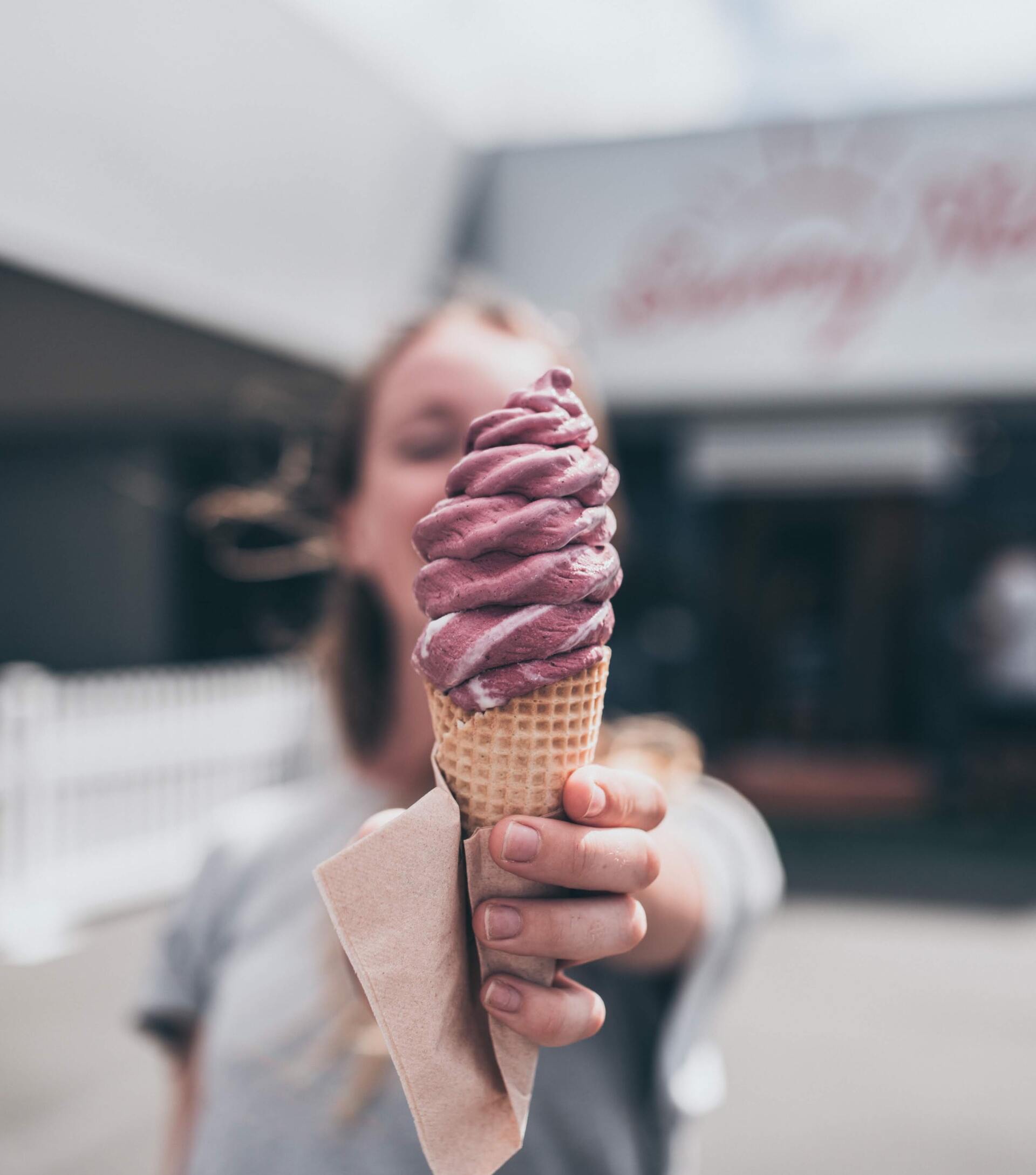 A woman is holding a purple ice cream cone in her hand 