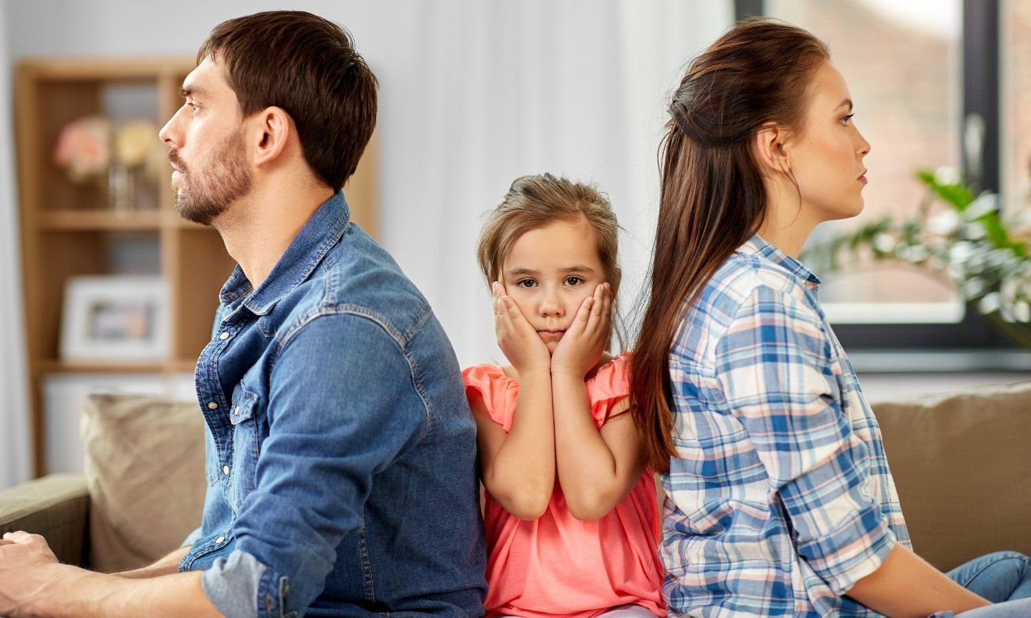 Parents facing away from each other with a child in between, looking concerned.