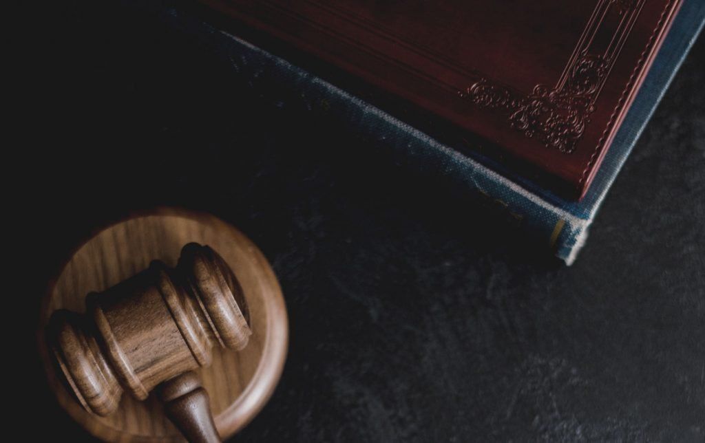Wooden gavel and book on a dark surface, representing law and justice.