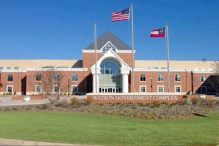 Wainson Government Complex building with US and Georgia flags waving in front of a blue sky.