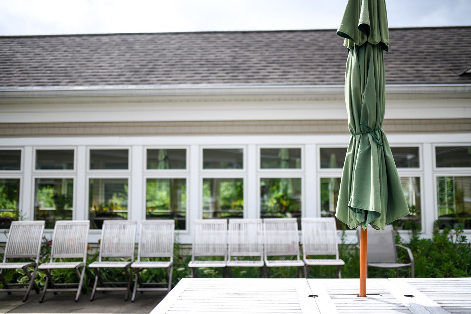 Outdoor seating area with umbrella near Bellamy Assisted Living community building
