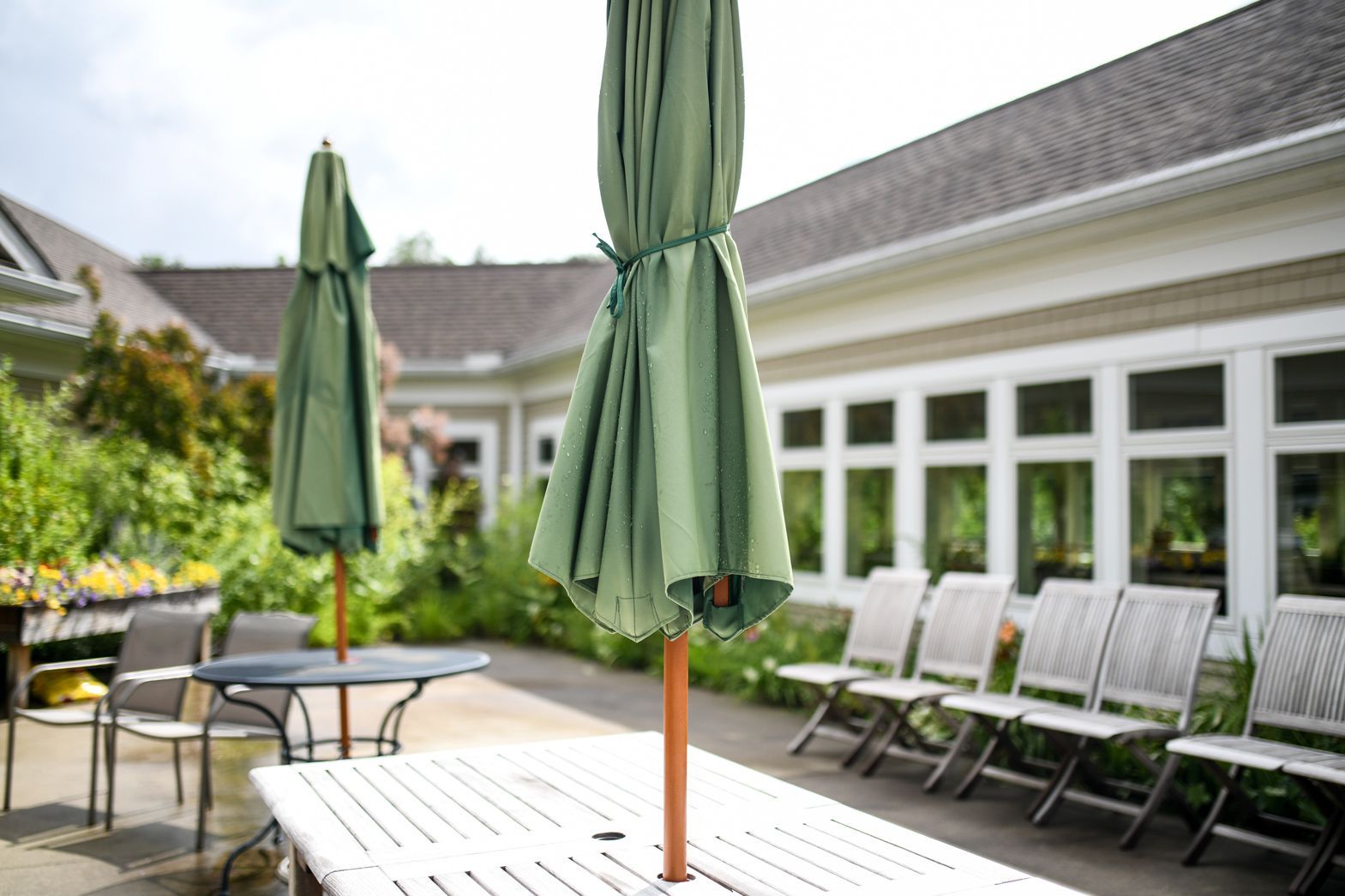 Courtyard seating with umbrellas under bright sunlight at Bellamy Assisted Living