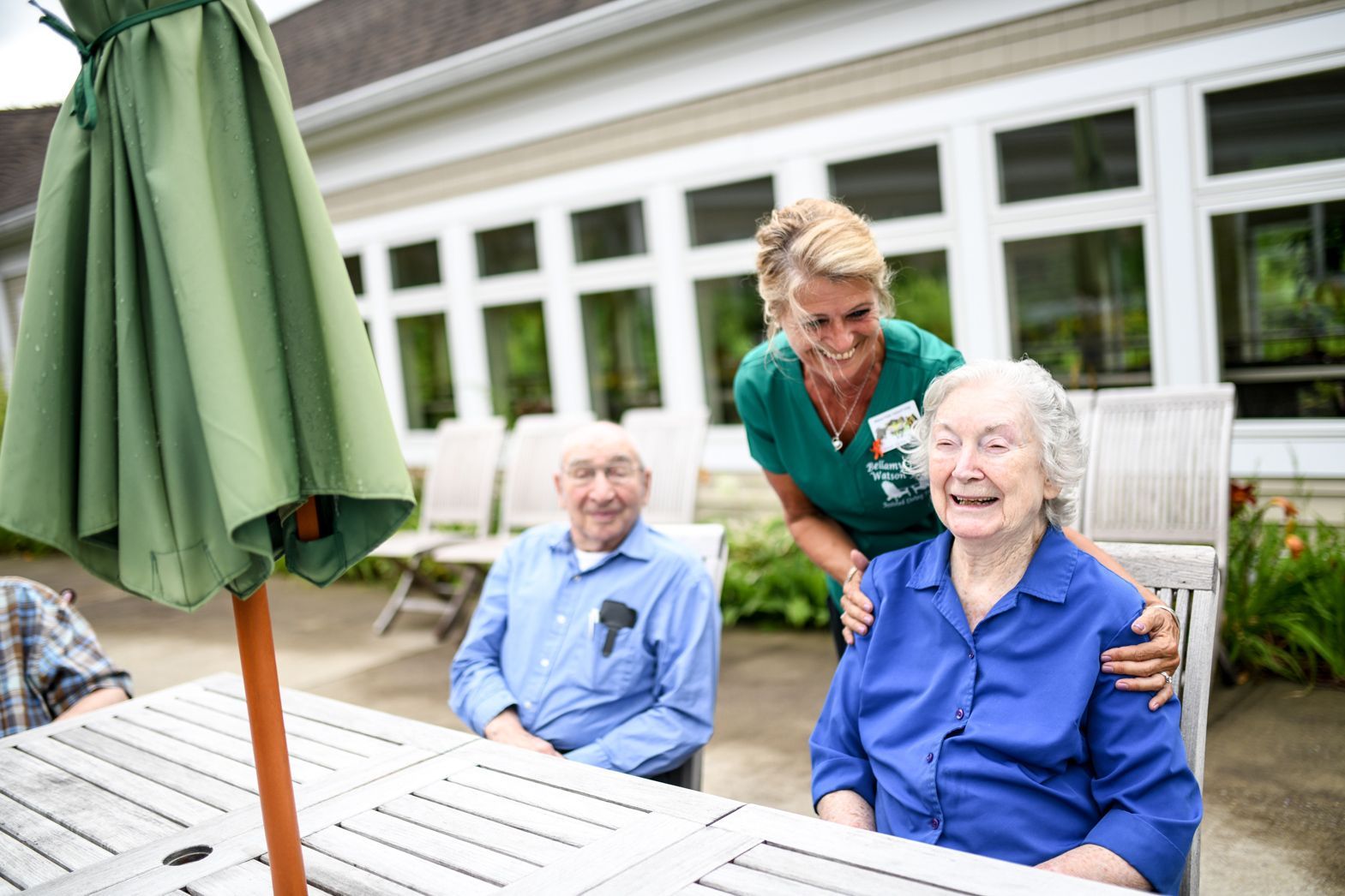 Caregiver chatting with residents on the outdoor patio at Bellamy Assisted Living