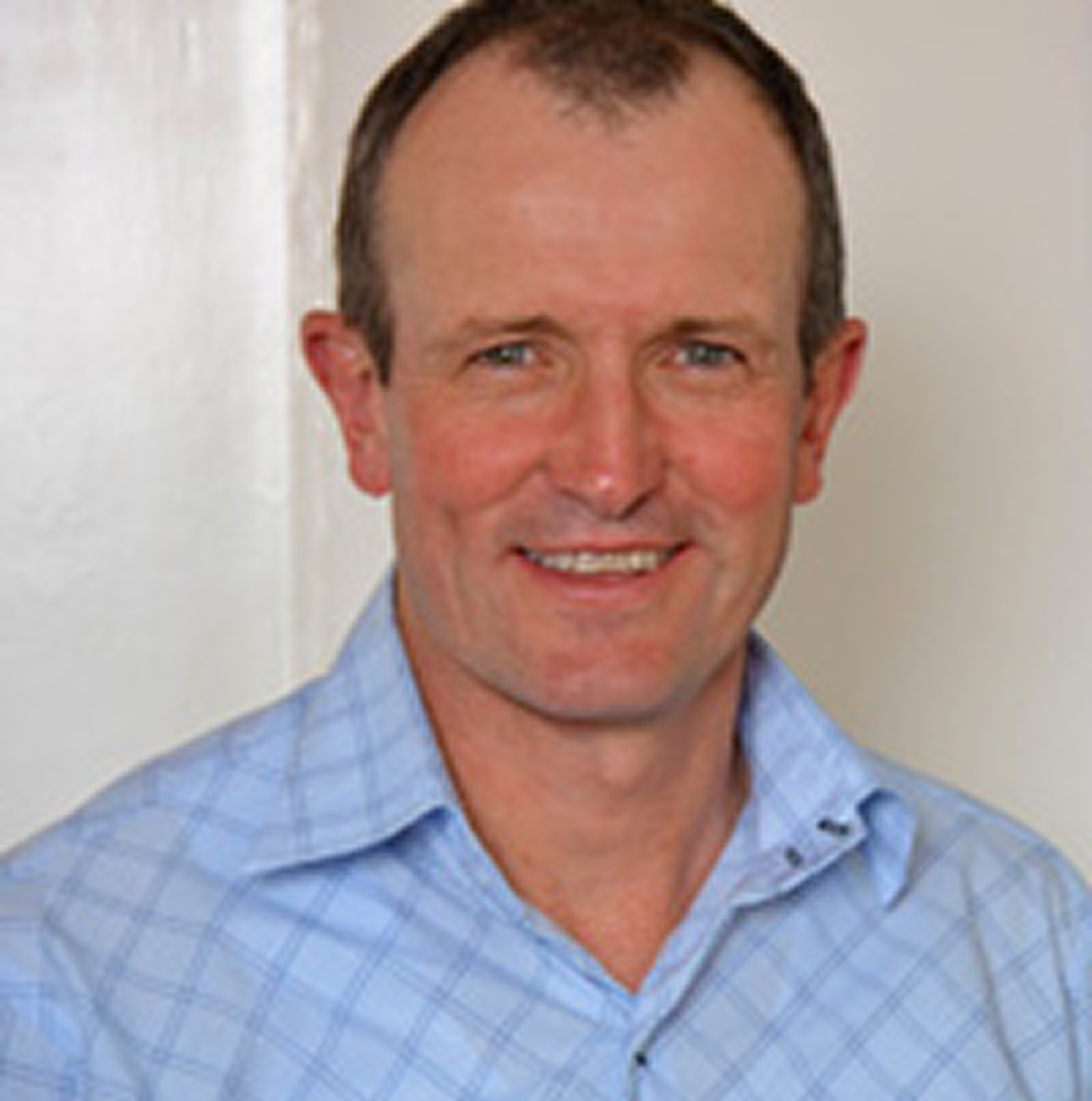 A man in a blue shirt is smiling for the camera