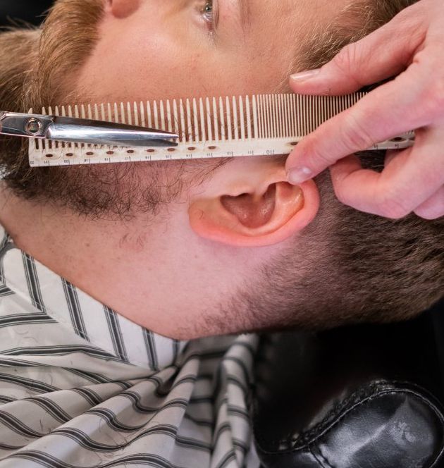A man is getting his hair cut with scissors and a comb