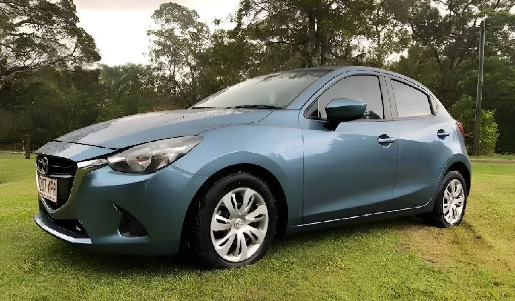 Blue Mazda 2 Parked On A Grassy Lawn