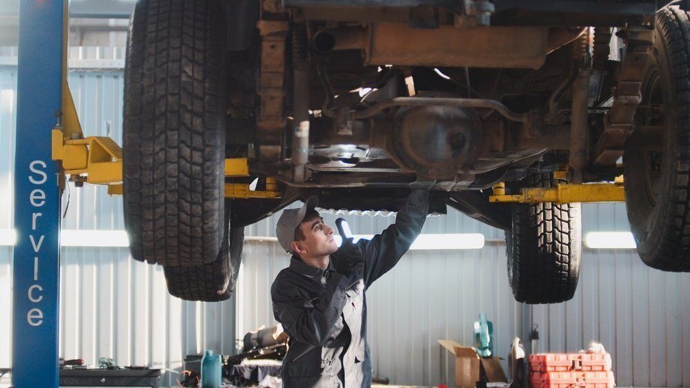 A Man Is Working Under A Truck On A Lift In A Garage — Browns Autobahn In Nambour, QLD