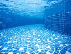 Empty blue tiled swimming pool with underwater view and rippling light reflections