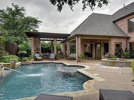Backyard pool and patio beside a brick house with a covered seating area and lounge chairs