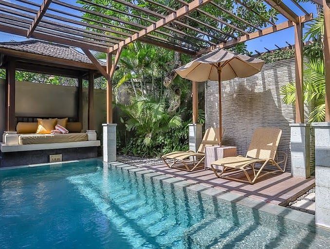 Modern backyard pool with lounge chairs, pergola, and shaded outdoor seating area