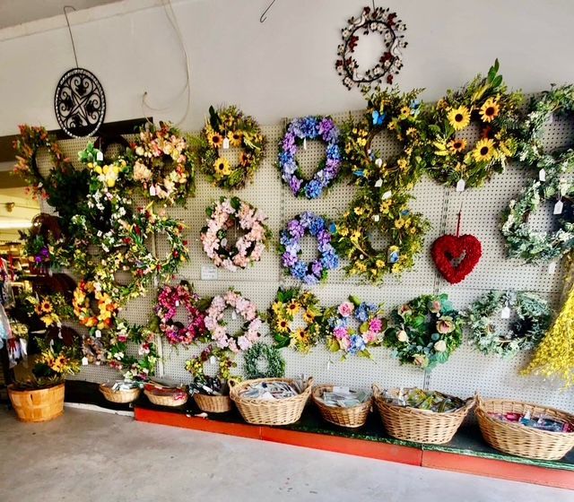 A wall filled with lots of wreaths and baskets