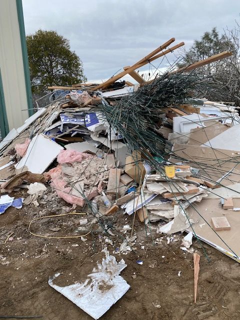 Collapsed pile of broken debris, wood, and twisted metal at a damaged construction site outdoors