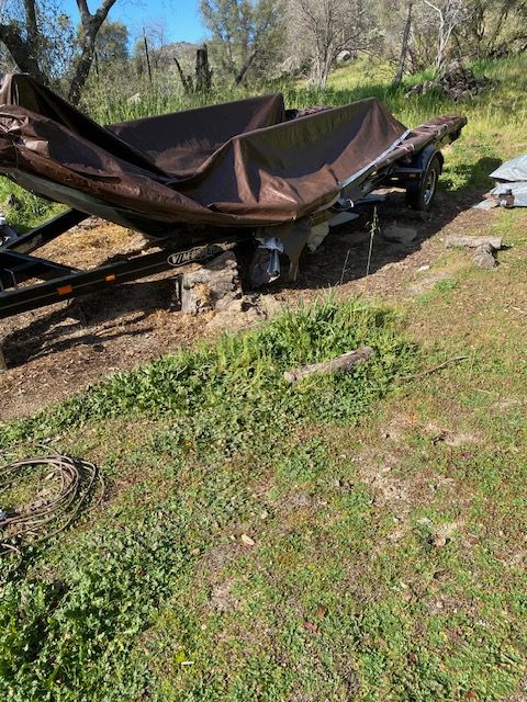 Collapsed brown tarp over a frame in a grassy yard, with trees and a blue sky in the background