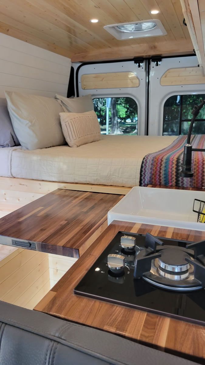 A camper van with a bed and a stove top oven.