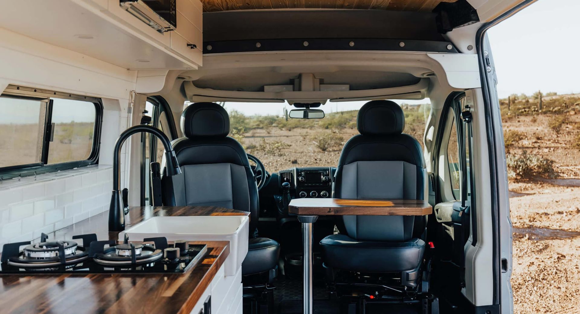 The inside of a camper van with a table and chairs.