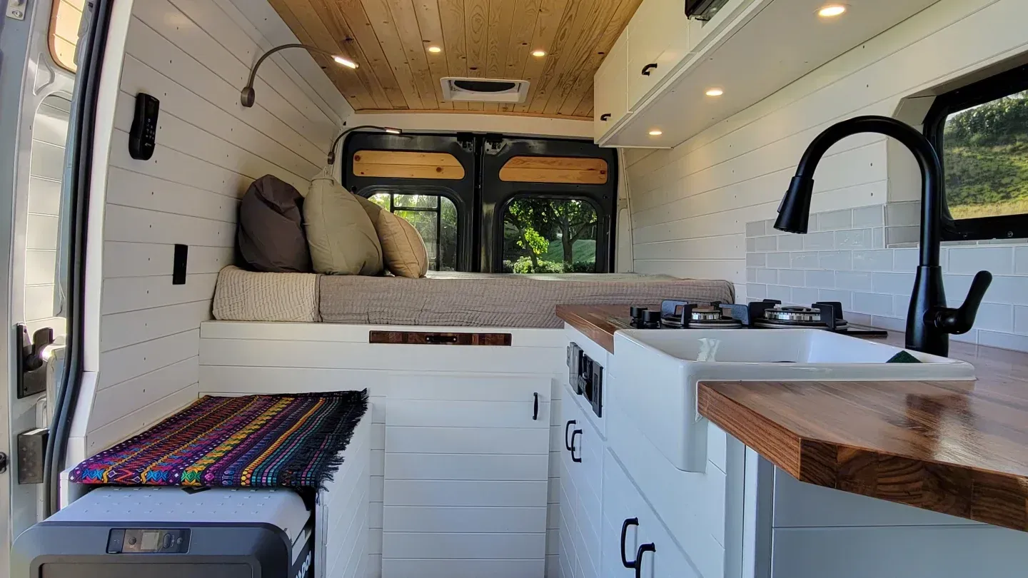 The inside of a camper van with a bed and a sink.