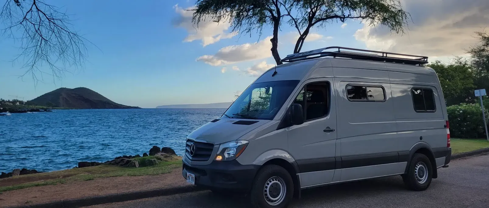 A van is parked on the side of the road next to a body of water.