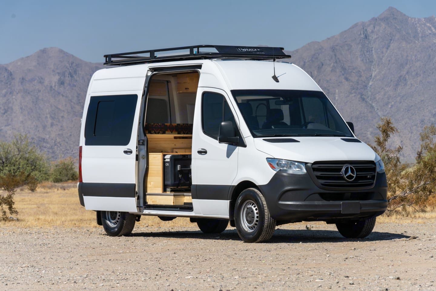 Sprinter van with open doors parked by mountainside road available for rental by Mana Vans in Kula, Maui, HI.