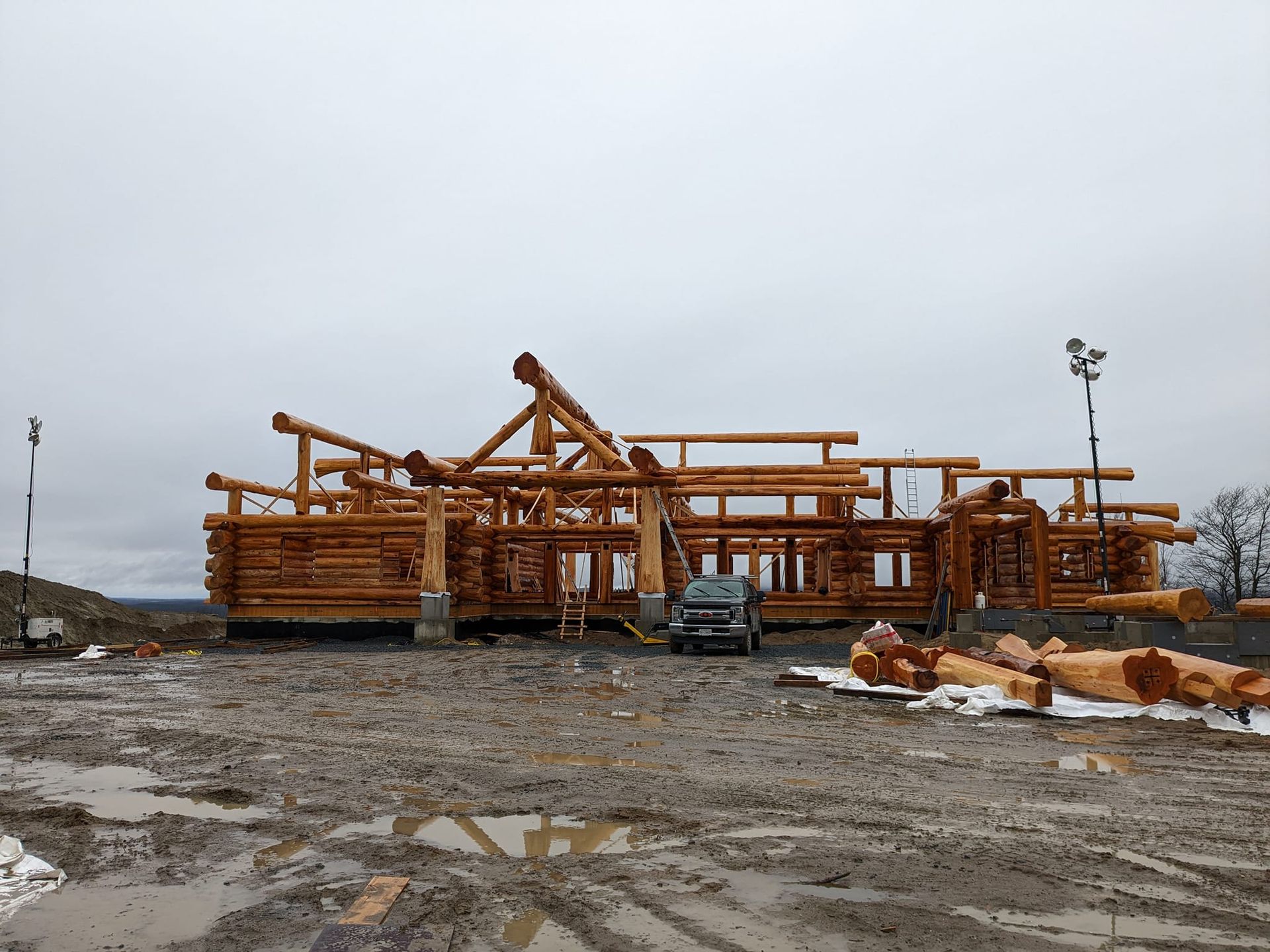 Structure en bois partiellement construite sur un chantier boueux sous un ciel couvert