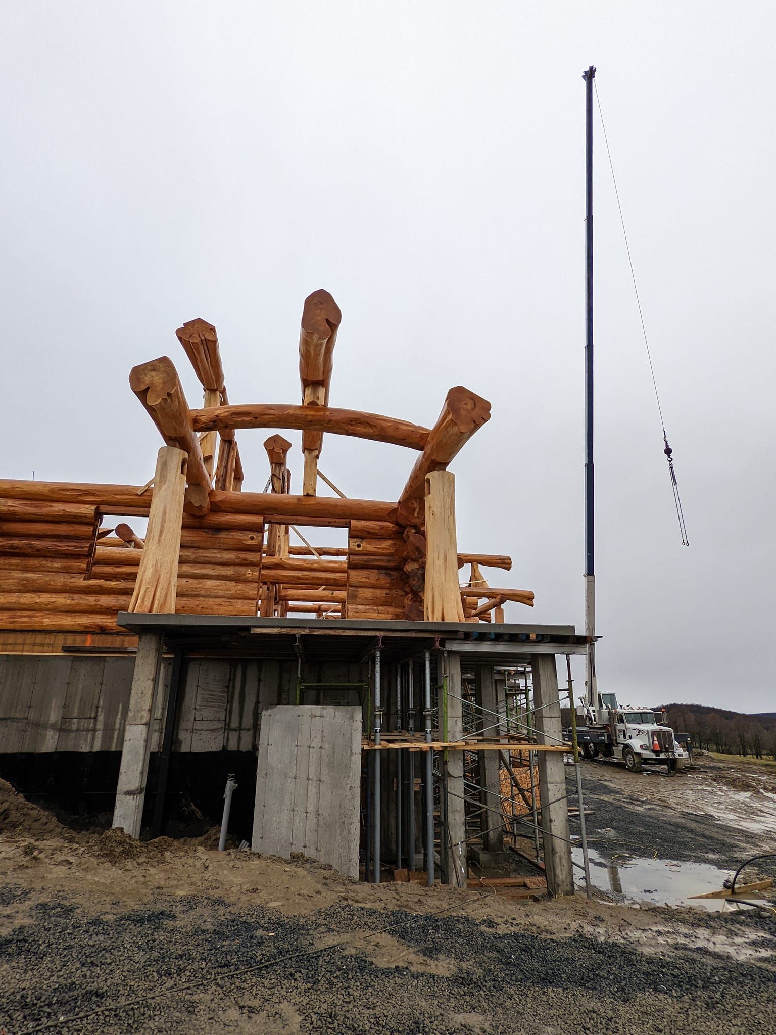Sculpture en bois sur un socle en béton, sur un rivage rocheux sous un ciel gris