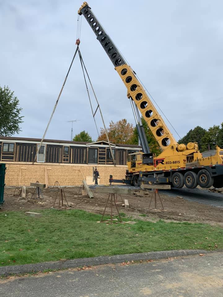 Une grue jaune soulève une section au-dessus d'un bâtiment en briques sur un chantier de construction