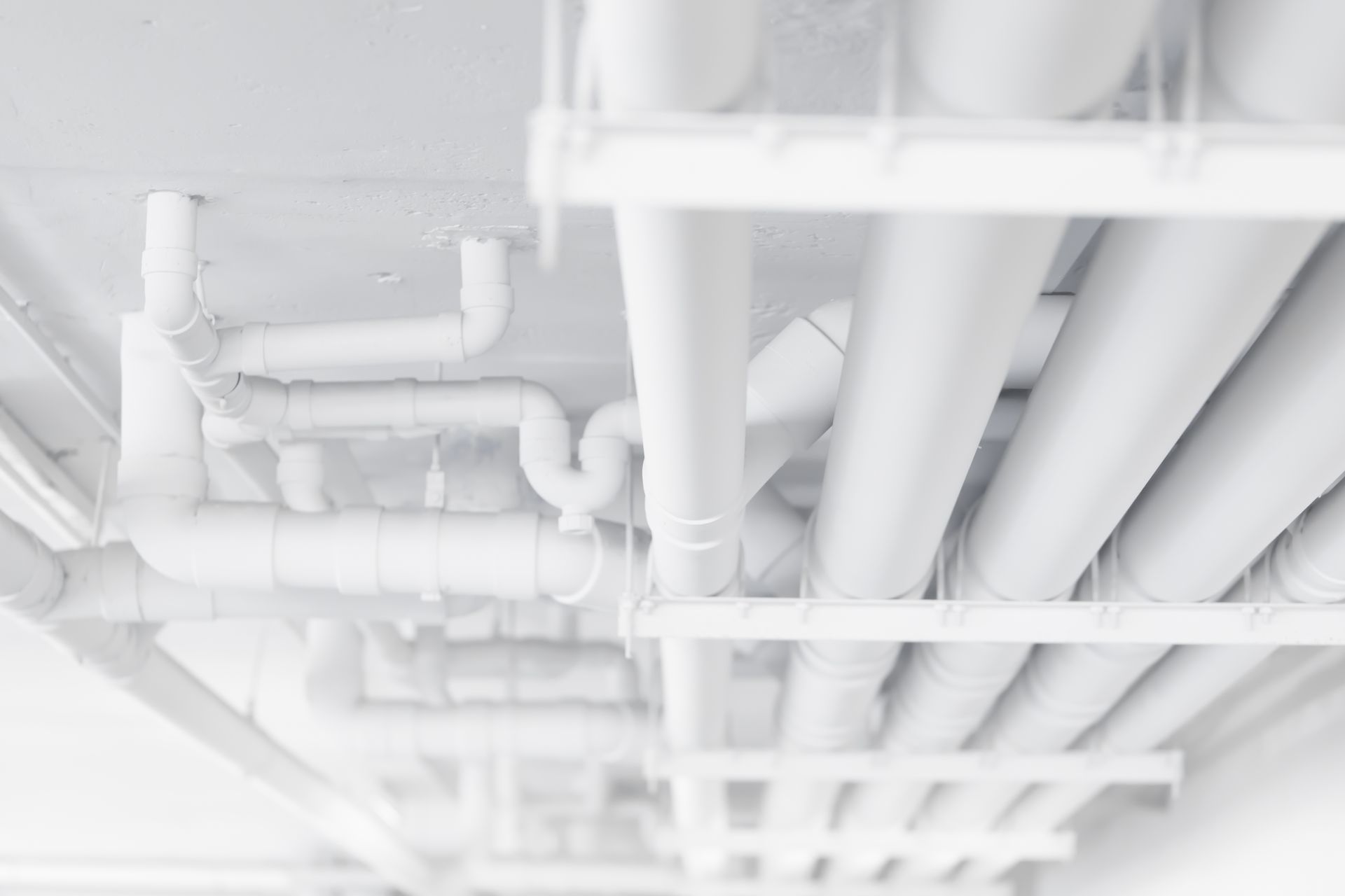 White pipes and fittings attached to a white ceiling.
