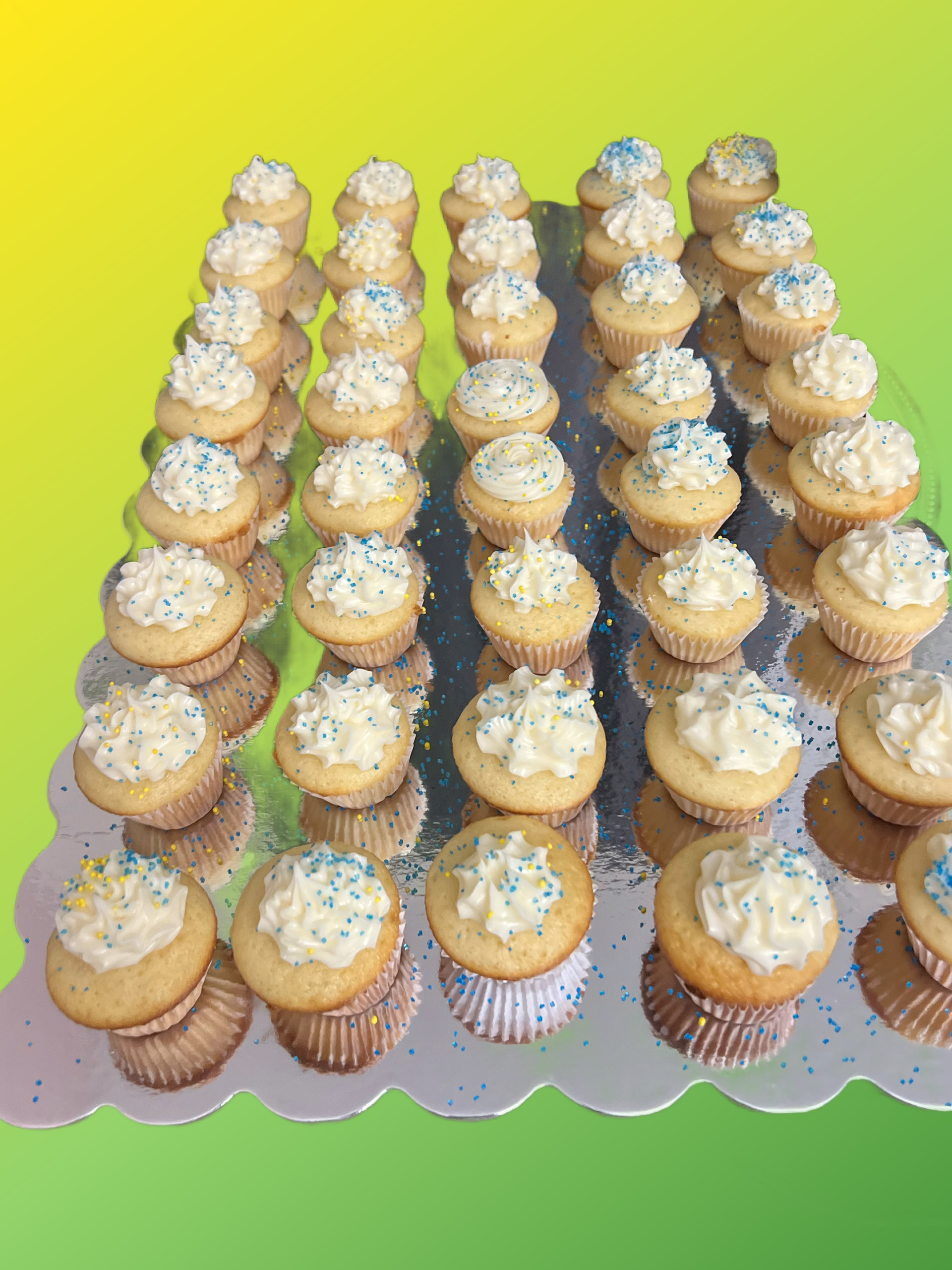 A tray of cupcakes with white frosting and blue sprinkles