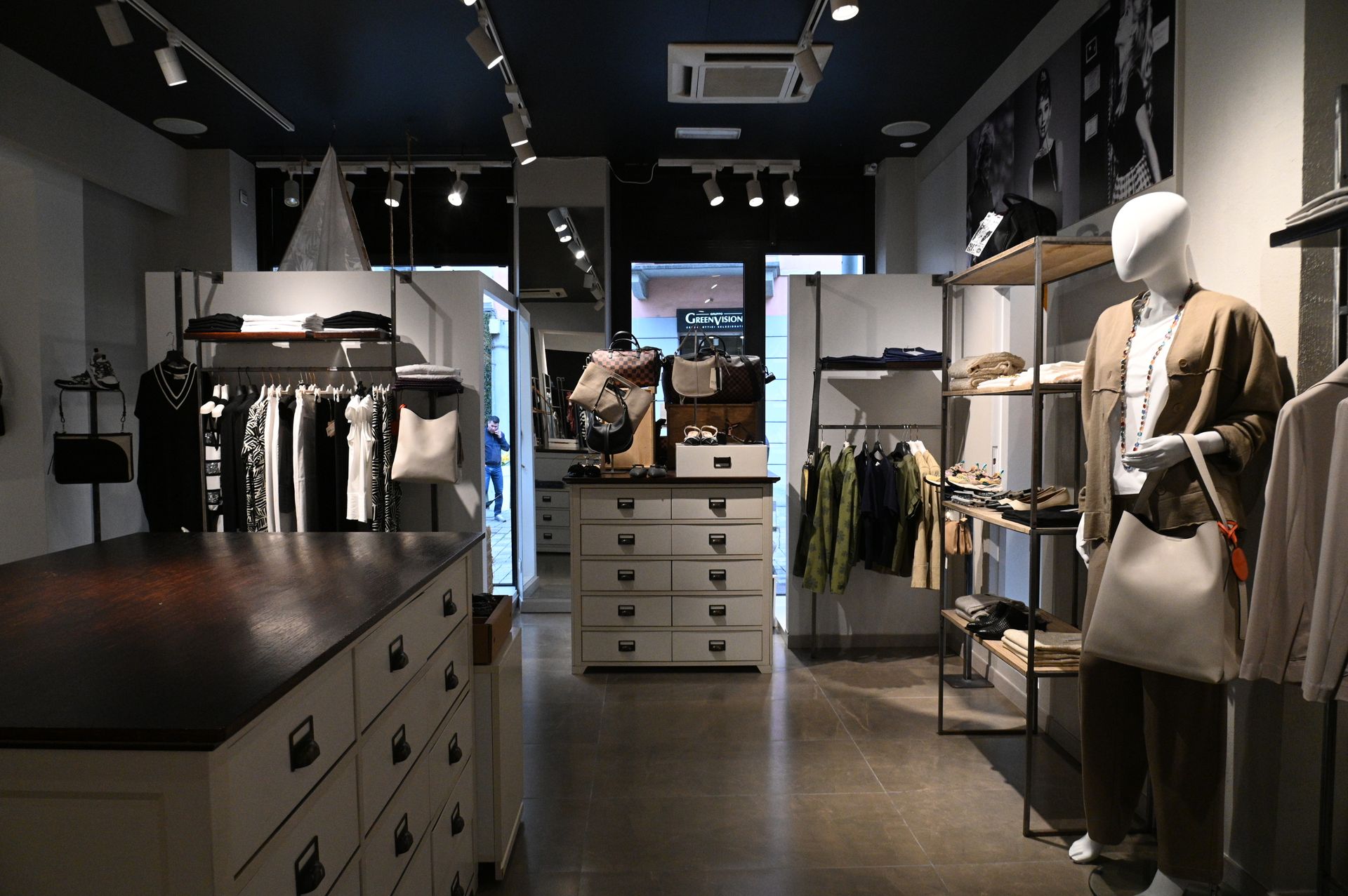 Interno di un negozio di abbigliamento con manichini, scaffali con vestiti e scaffali espositivi.