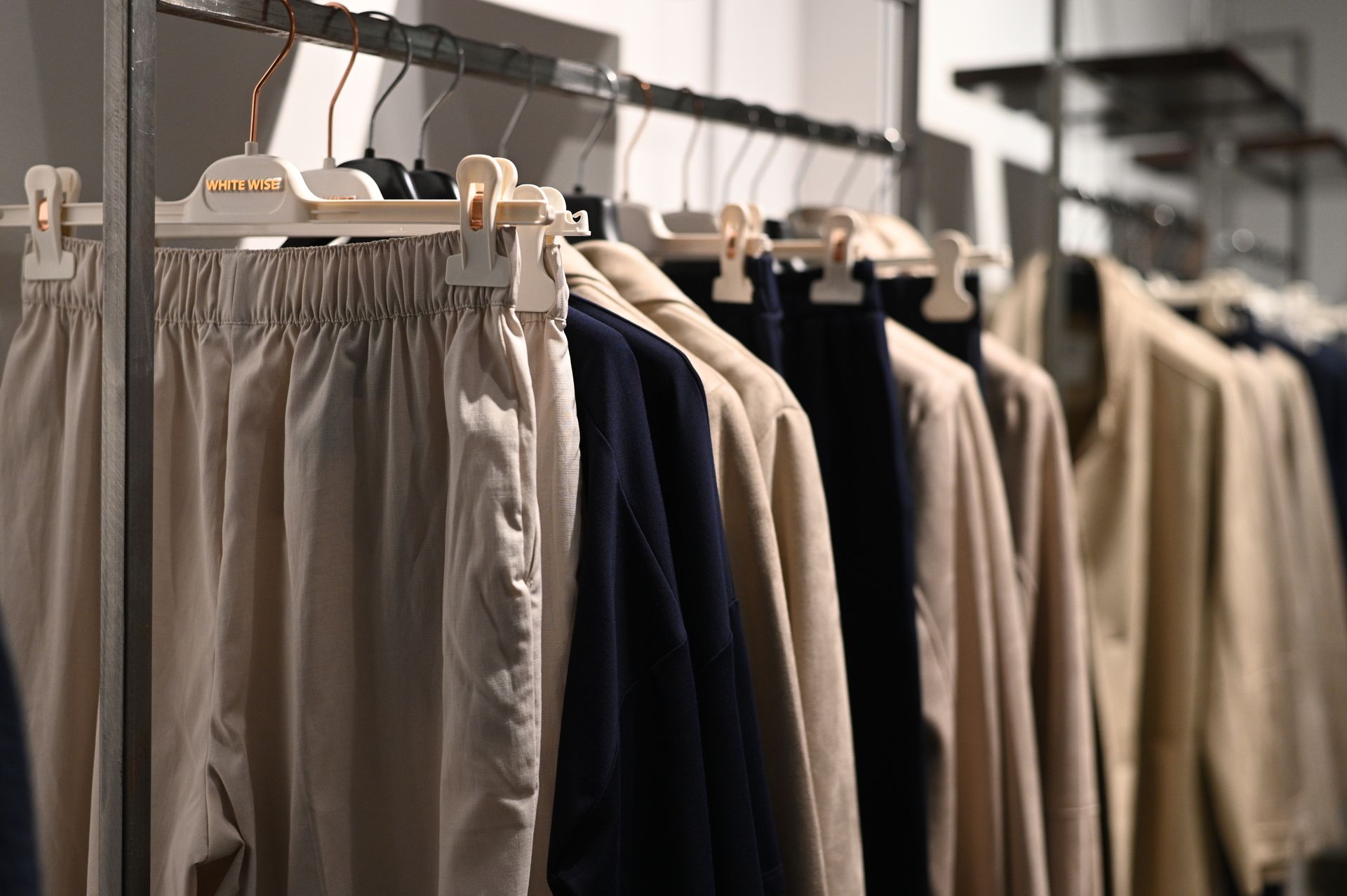 Espositore con vari indumenti, tra cui pantaloni e giacche, in un negozio di abbigliamento.