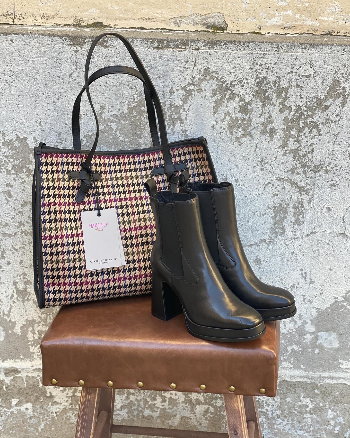 Borsa di tela con stivali su uno sgabello contro una parete ruvida.