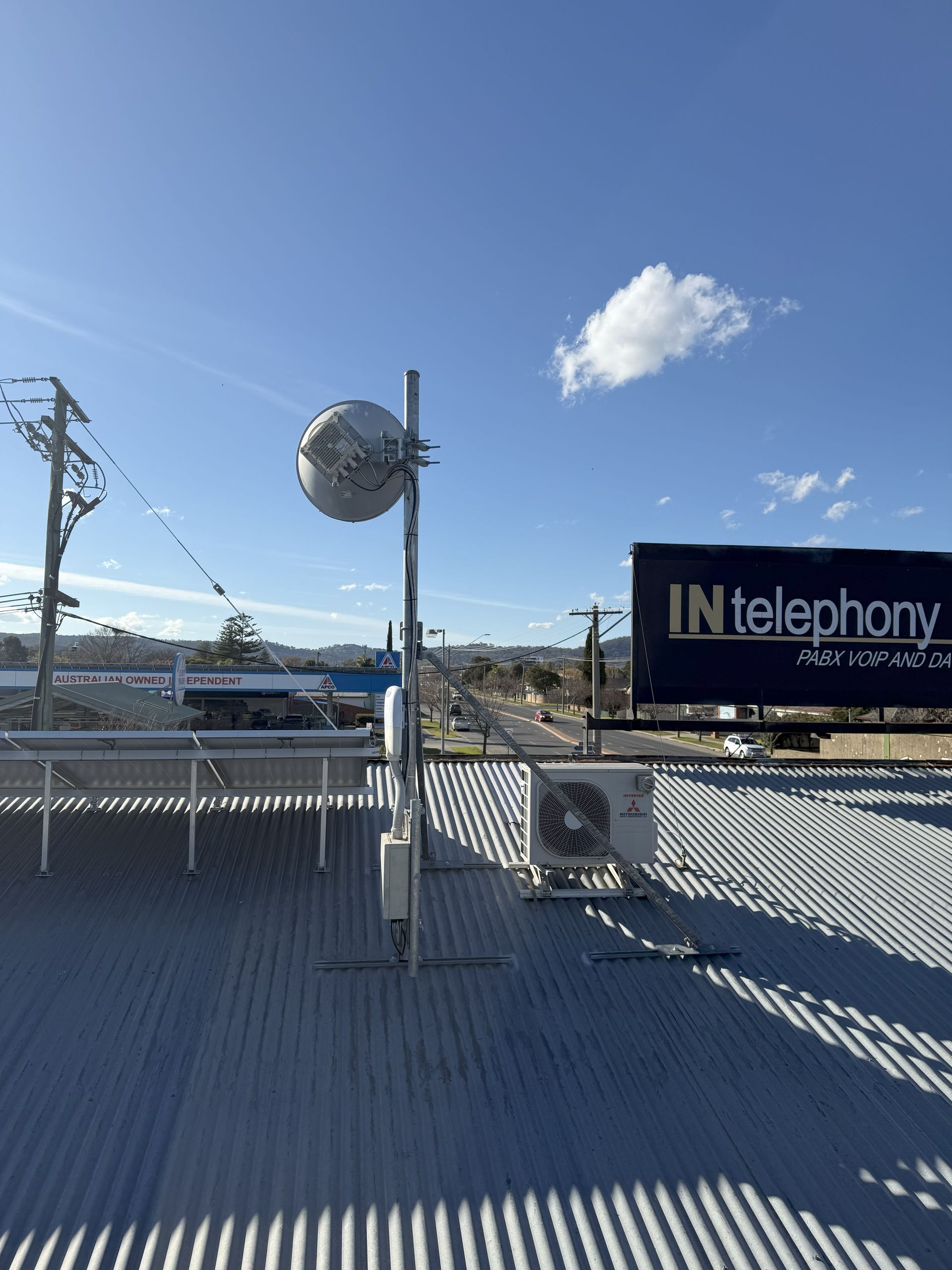 Rooftop with globe-shaped antenna, signage, and blue sky — INtelephony In Albury, NSW