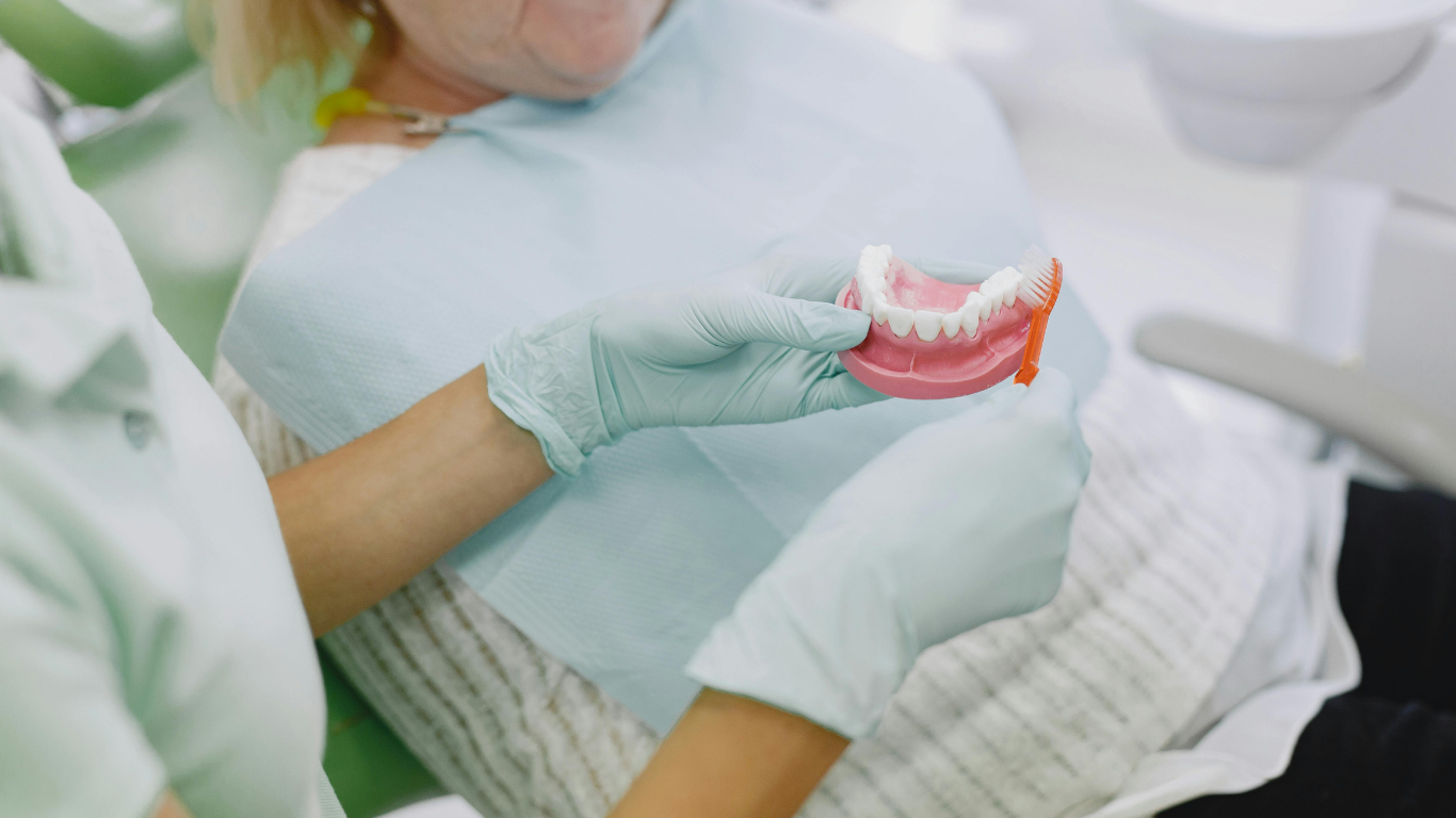 Dentist holding a dental mold in gloved hands during a patient consultation