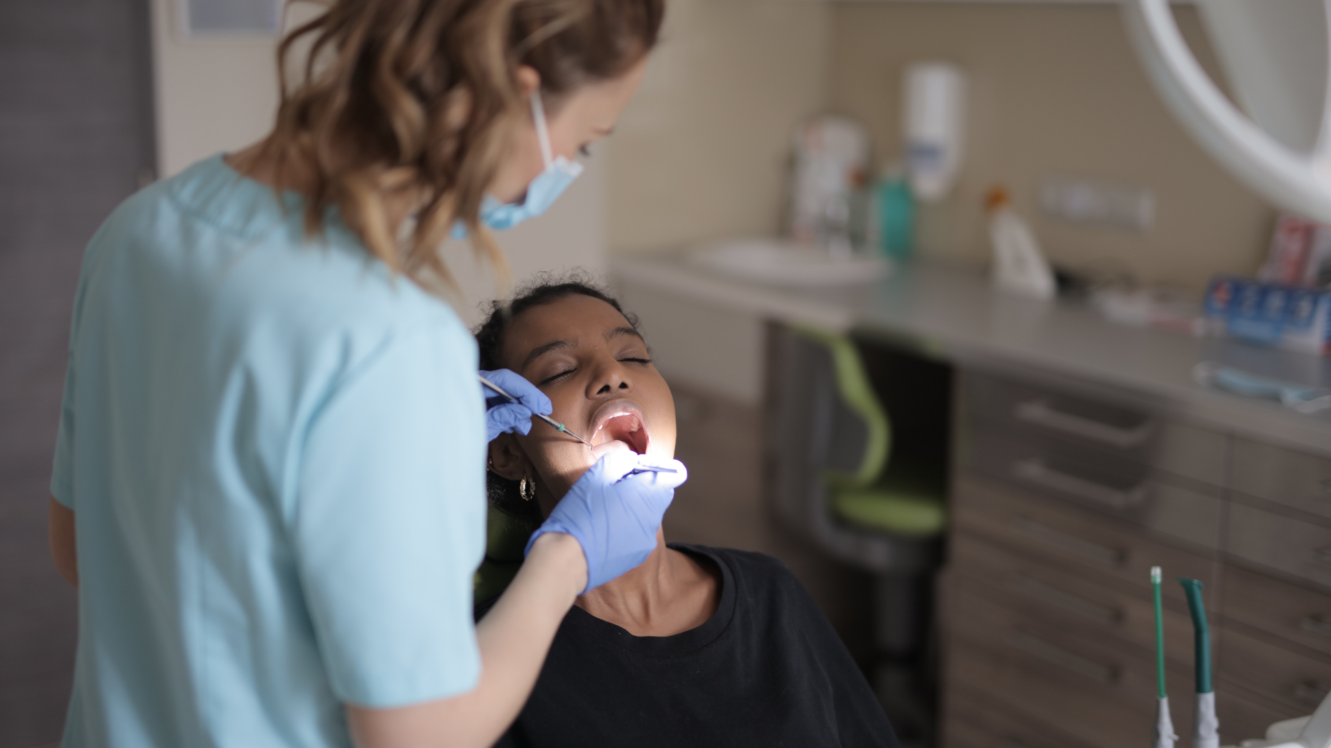 A woman is getting her teeth examined by a dentist in a dental office.