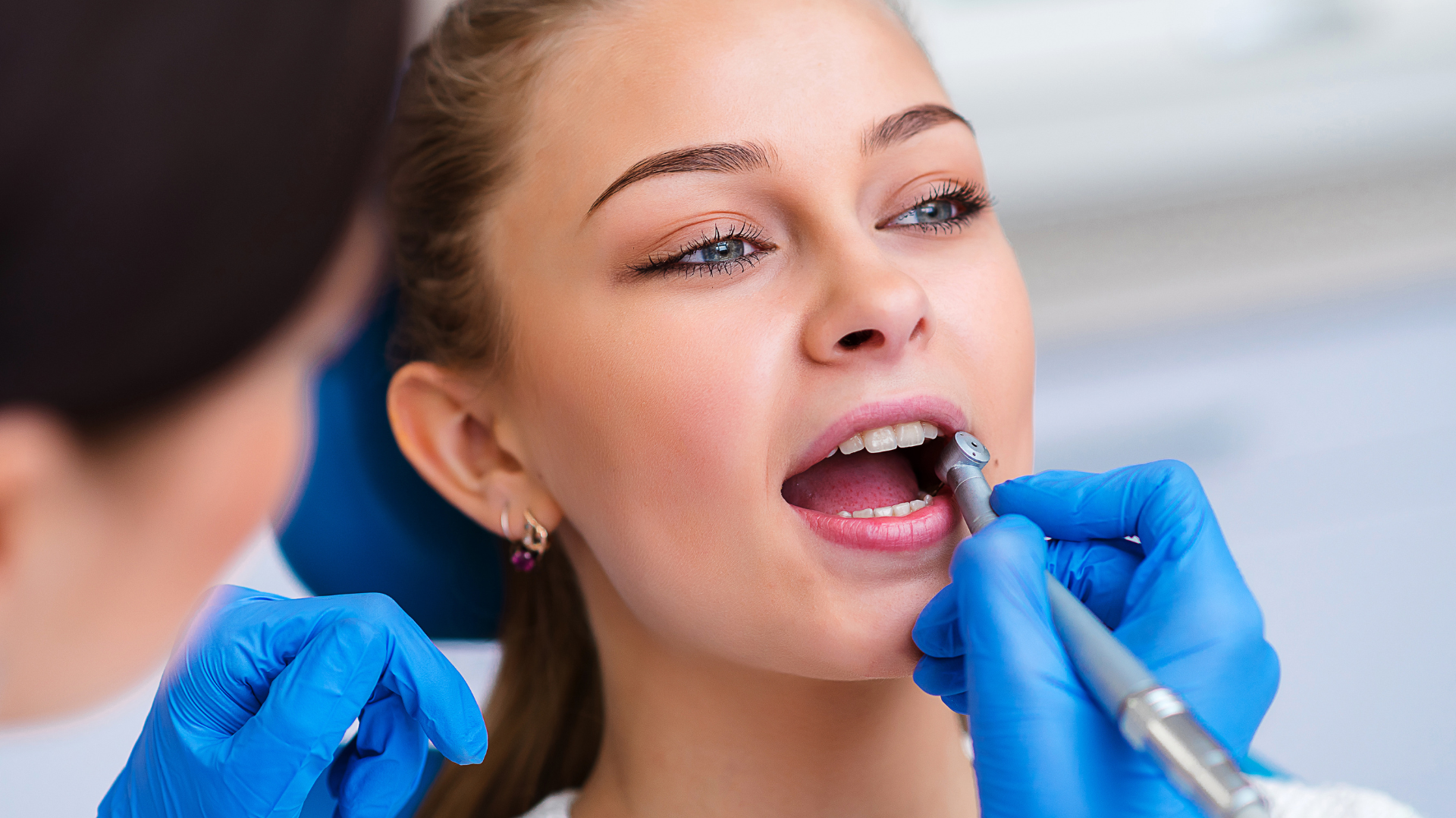 A woman is getting her teeth examined by a dentist.