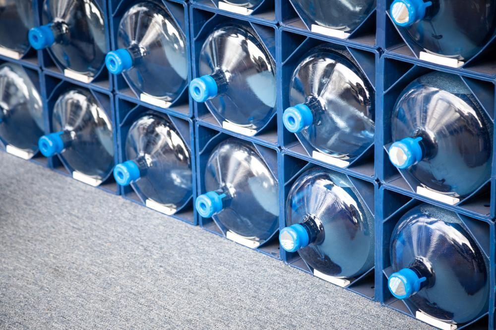 A Grid of Large, Clear Plastic Water Jugs With Blue Caps Stored in a Blue Plastic — Cool Blue Ice & Water in Armidale, NSW