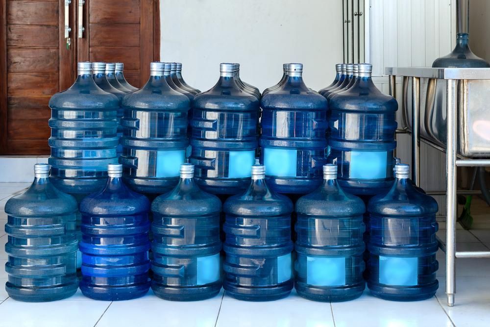 A Group of Large, Blue Plastic Water Jugs Arranged in Two Rows on a Tiled Floor — Cool Blue Ice & Water in Taminda, NSW