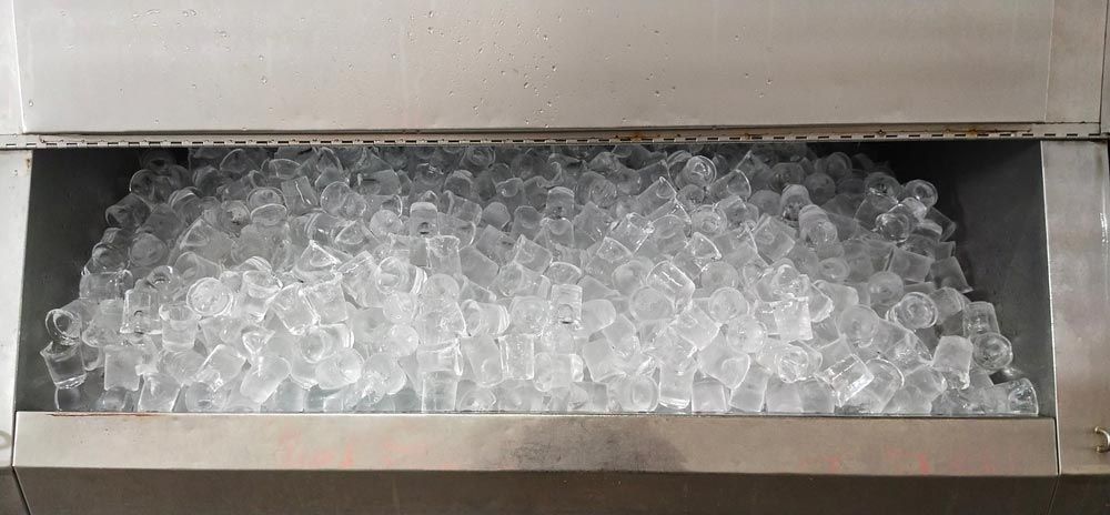 A Bin Filled With Clear, Cube-shaped Ice, Housed Inside a Stainless Steel Ice Machine — Cool Blue Ice & Water in Taminda, NSW
