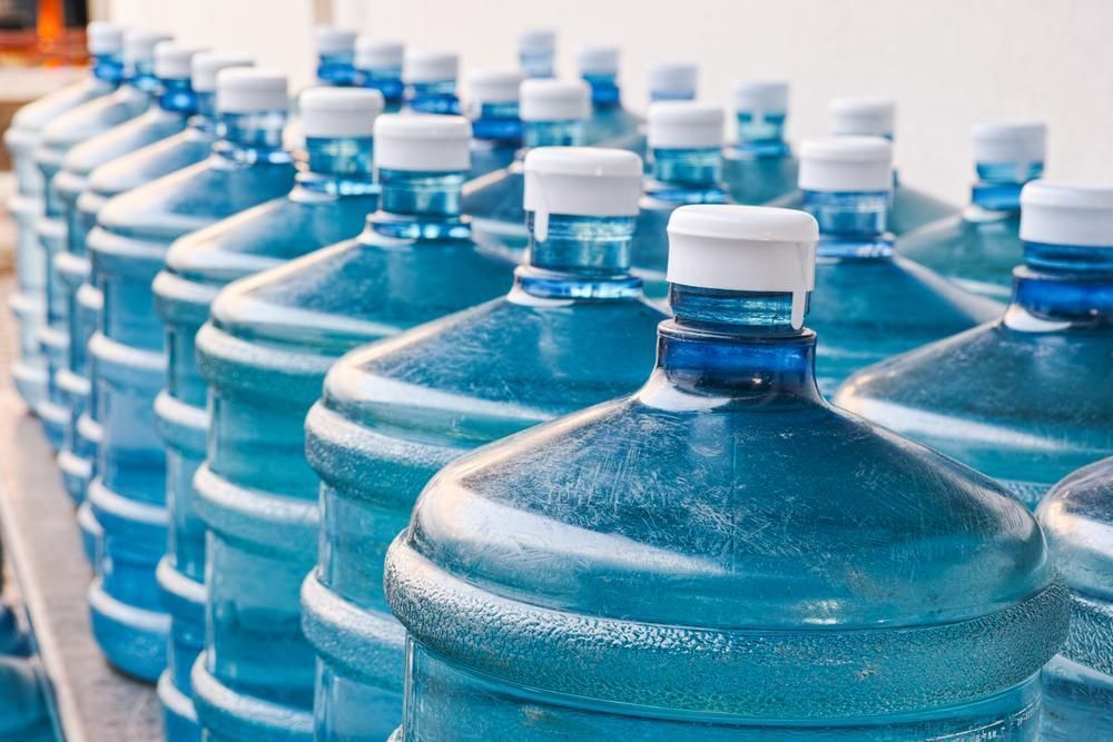 Rows of Large, Blue Plastic Water Jugs With White Caps Arranged on a Shelf — Cool Blue Ice & Water in Coolah, NSW