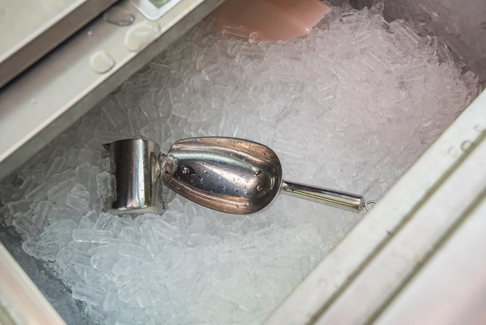 A Metal Ice Scoop Lying Partially Submerged Inside a Bin Filled With Crushed Ice — Cool Blue Ice & Water in Scone, NSW