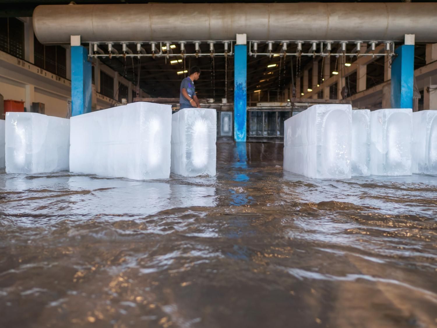 Large Blocks of Ice Sit on a Wet Warehouse Floor With a Worker Visible — Cool Blue Ice & Water in Gunnedah, NSW