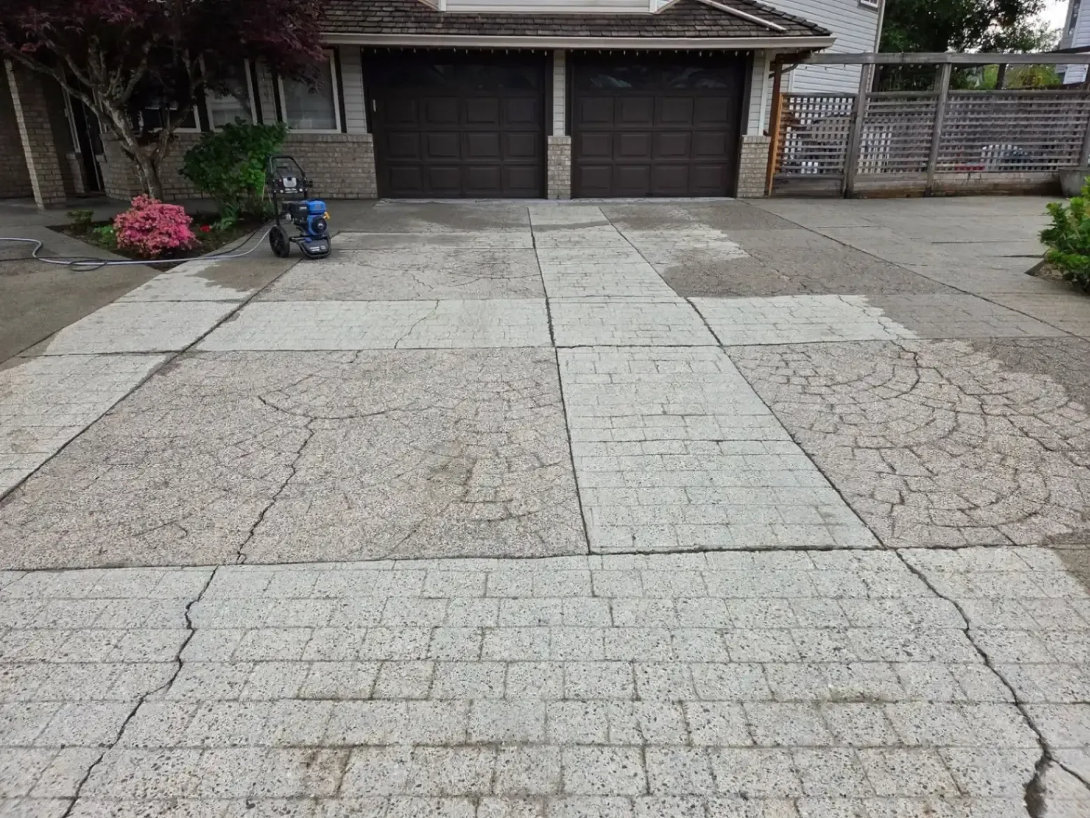 Driveway leading to a double garage with concrete pavers and a few potted plants.