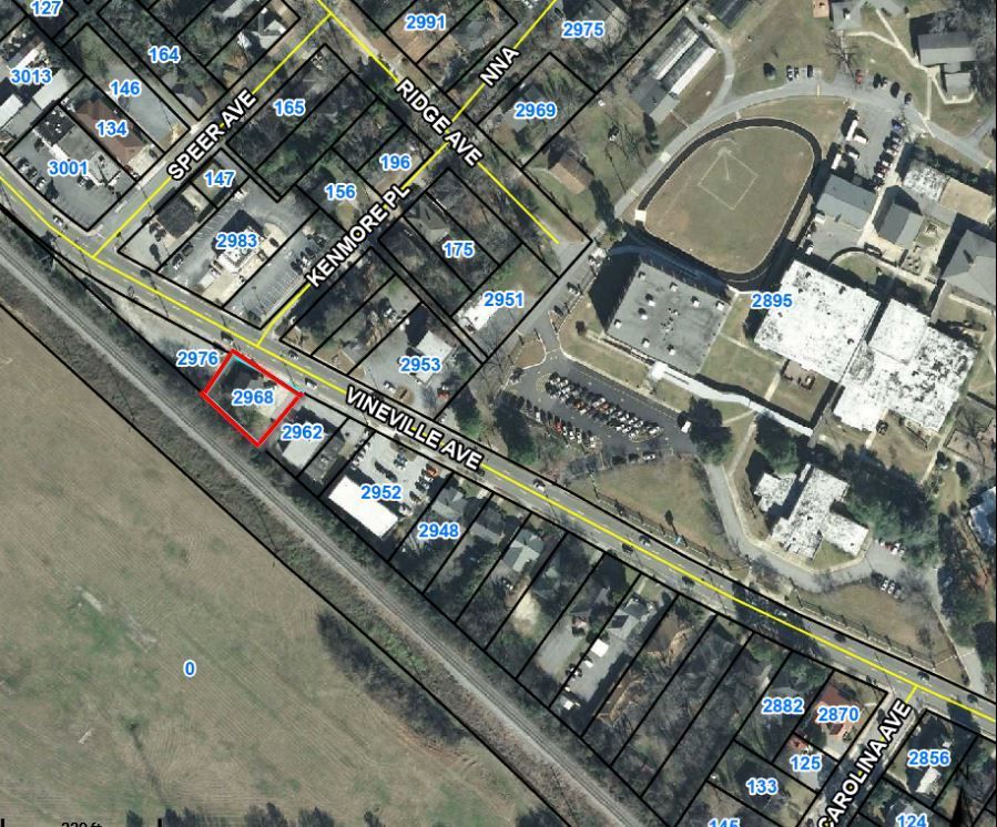 Aerial view of a residential neighborhood, with a red-circled spot near a road and canal.