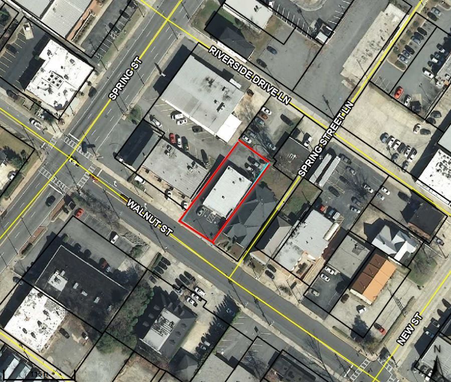 Aerial view of city blocks with a red-outlined building lot at a street corner.