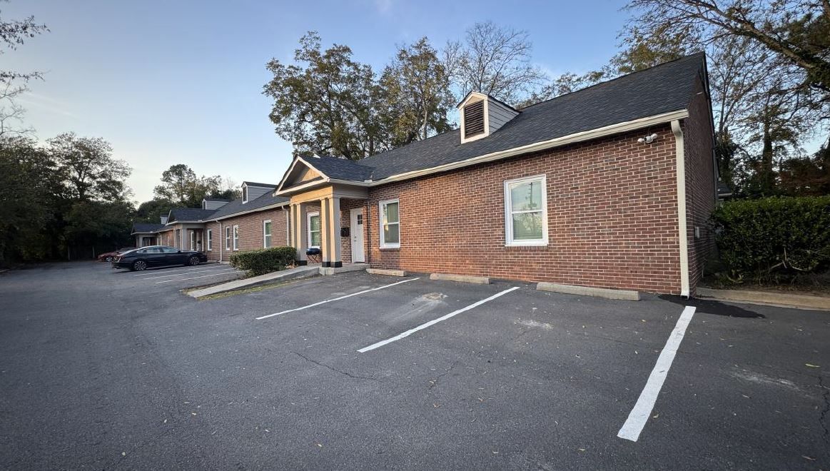 Brick office building with handicap parking spaces in a mostly empty lot at dusk