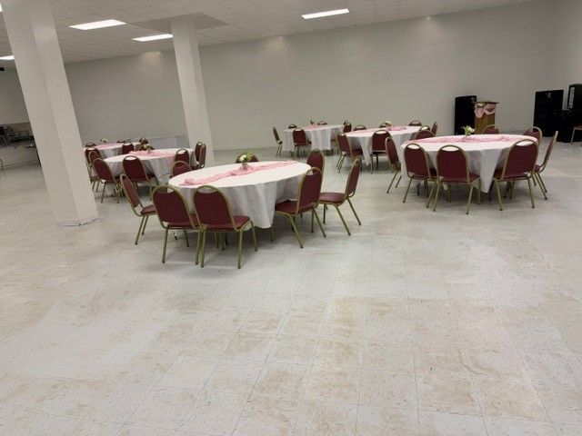 Empty banquet hall with round tables, red chairs, and white tablecloths in a spacious room