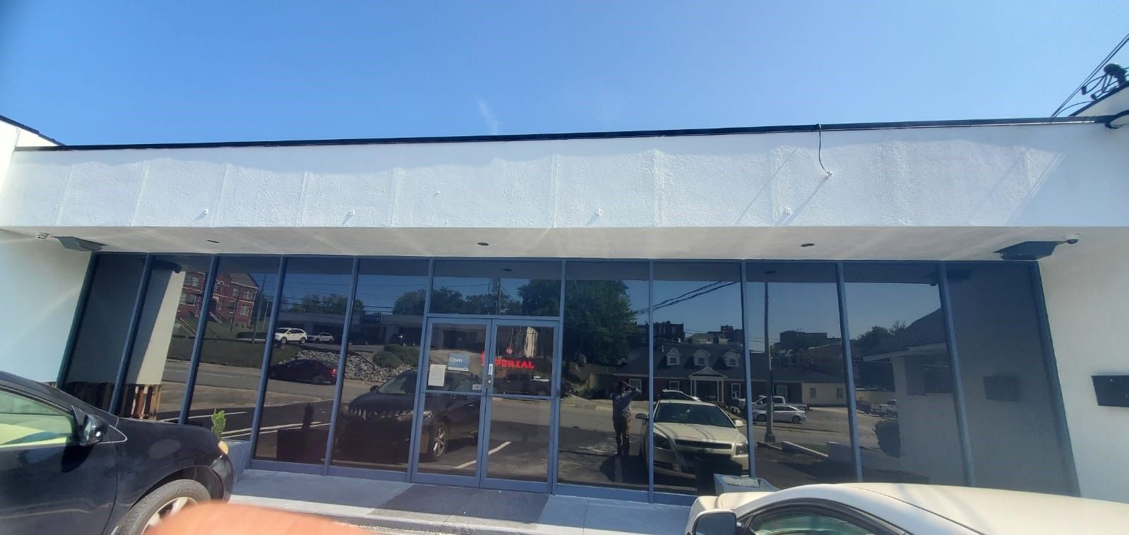 Storefront with large glass windows and a pale awning under a clear blue sky