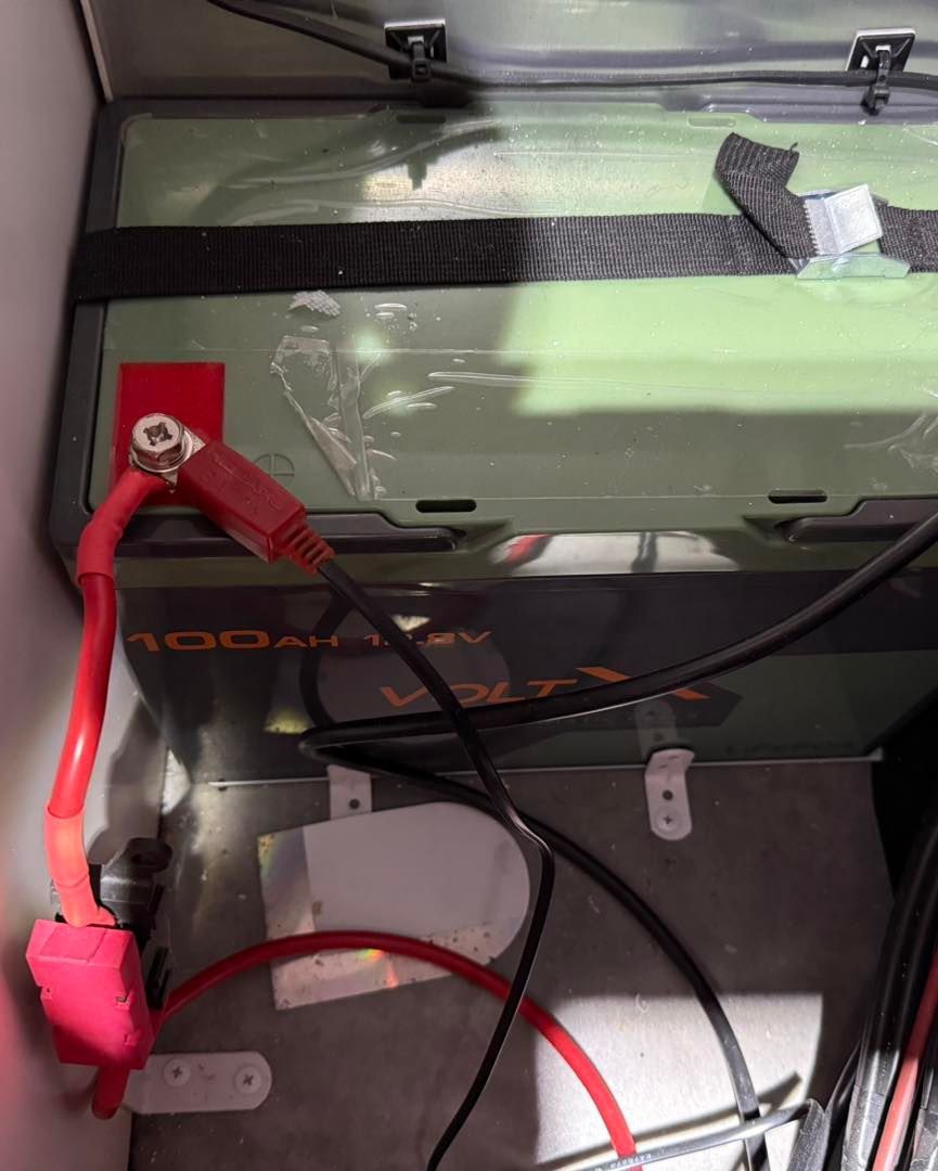 A Green Battery With Red and Black Wires — Gibbo's Auto Electrics & Air Conditioning Services in Belmont, NSW