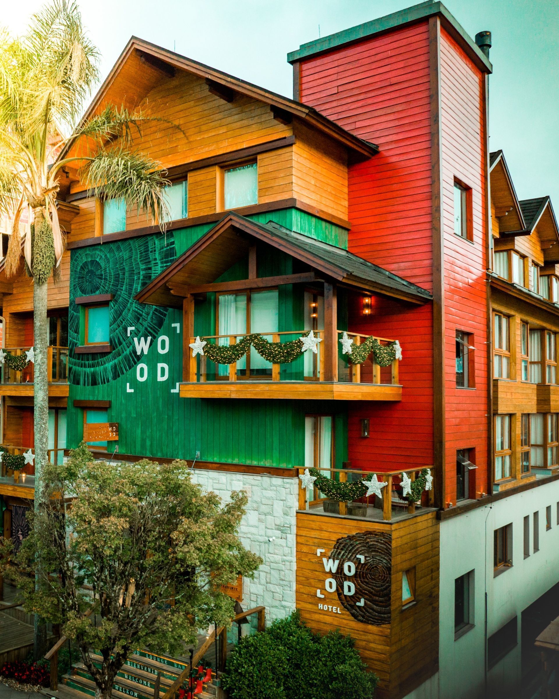 Casa colorida de vários andares com paredes e varandas vermelhas, verdes e laranjas em uma rua estreita.