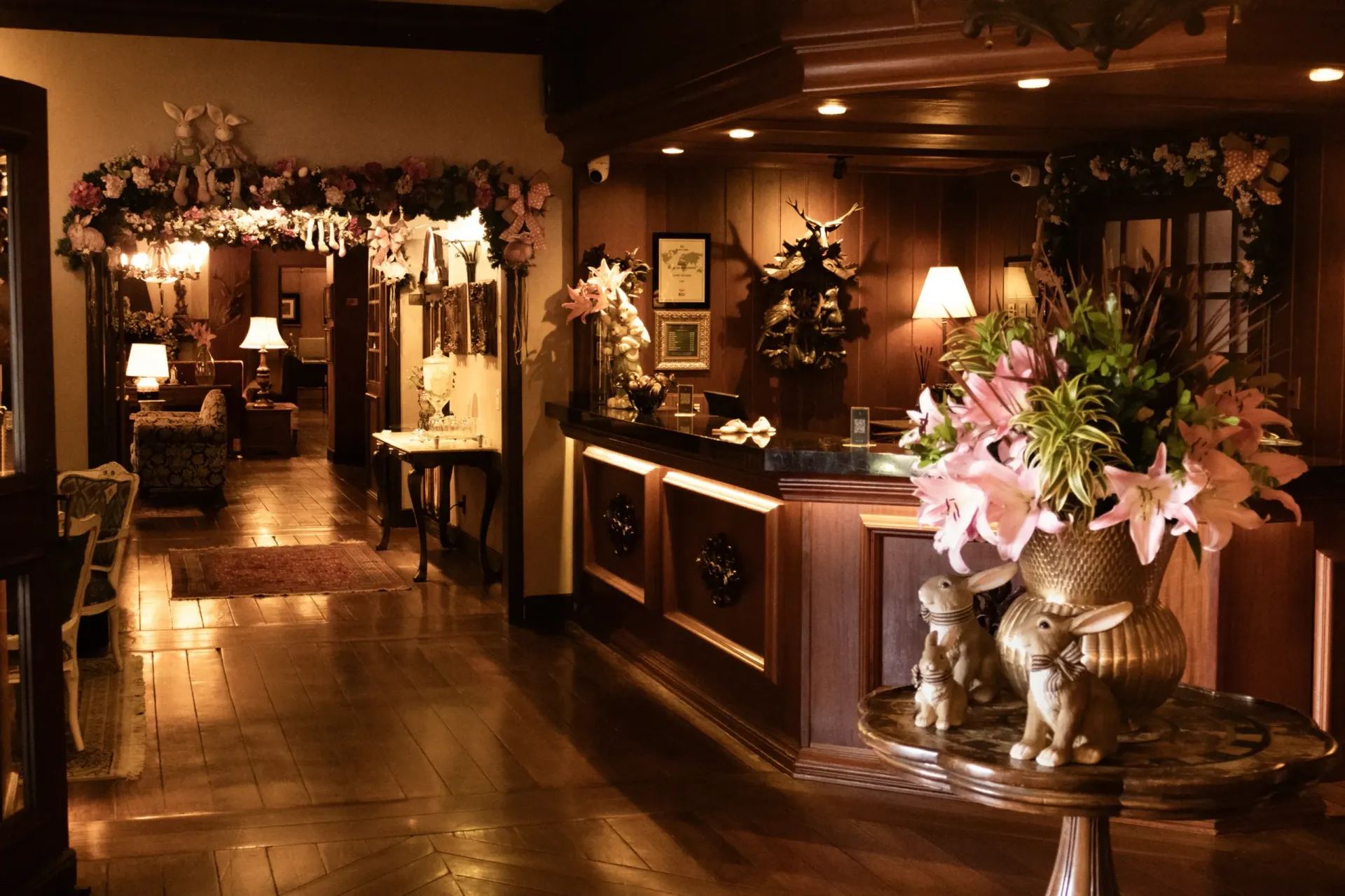 Hall de entrada elegante do hotel com iluminação aconchegante, decoração em madeira escura e arranjos florais.