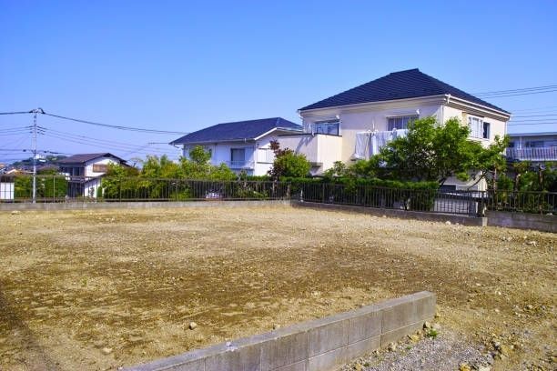 An empty lot in front of residential houses under a clear blue sky.